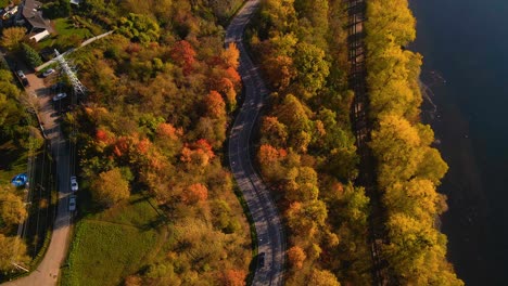 aerial shot of a car driving on winding road adjacent to railway alongside nemunas river in kaunas, lithuania, top down shot