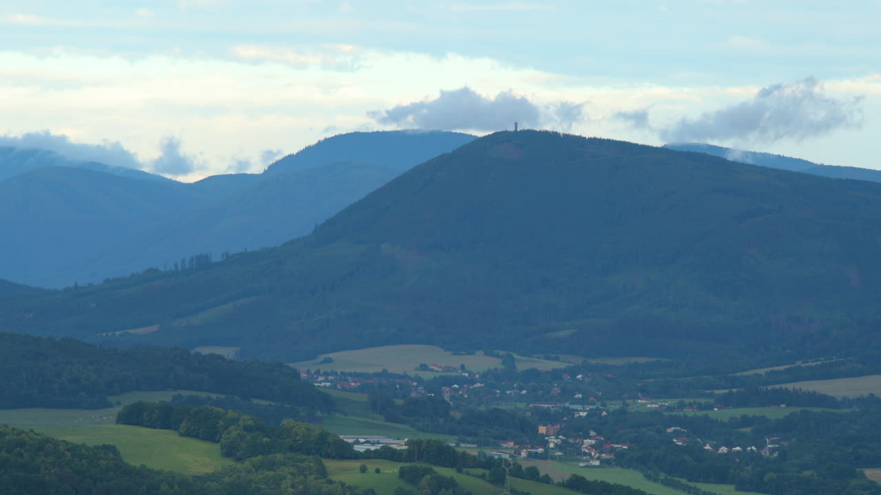 zoom en la cima de una montaña y nubes blancas moviéndose sobre un paisaje montañoso lleno de colinas durante un día soleado nubes bajas moviéndose sobre las colinas