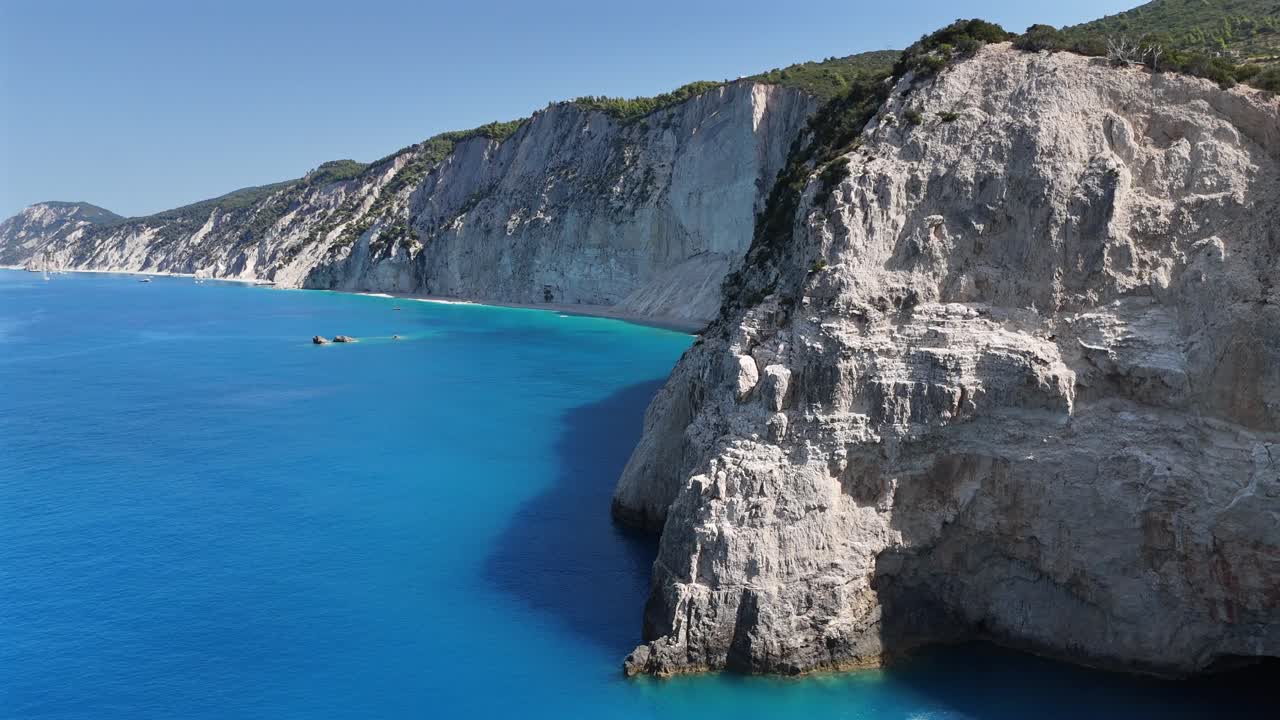 Lefkada,Aerial view pan right,panoramic view of the white steep cliffs meeting the mesmerizing turquoise calm seas.Beautiful tranquil nature and scenery,