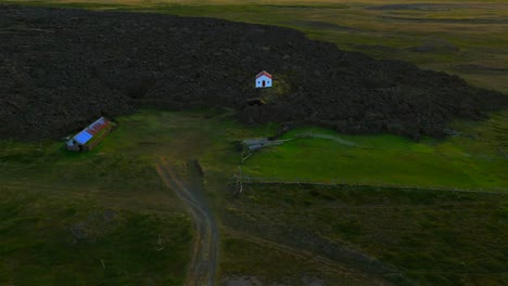 discover the charm of a solitary home in iceland, beautifully juxtaposed against ancient volcanic rock.