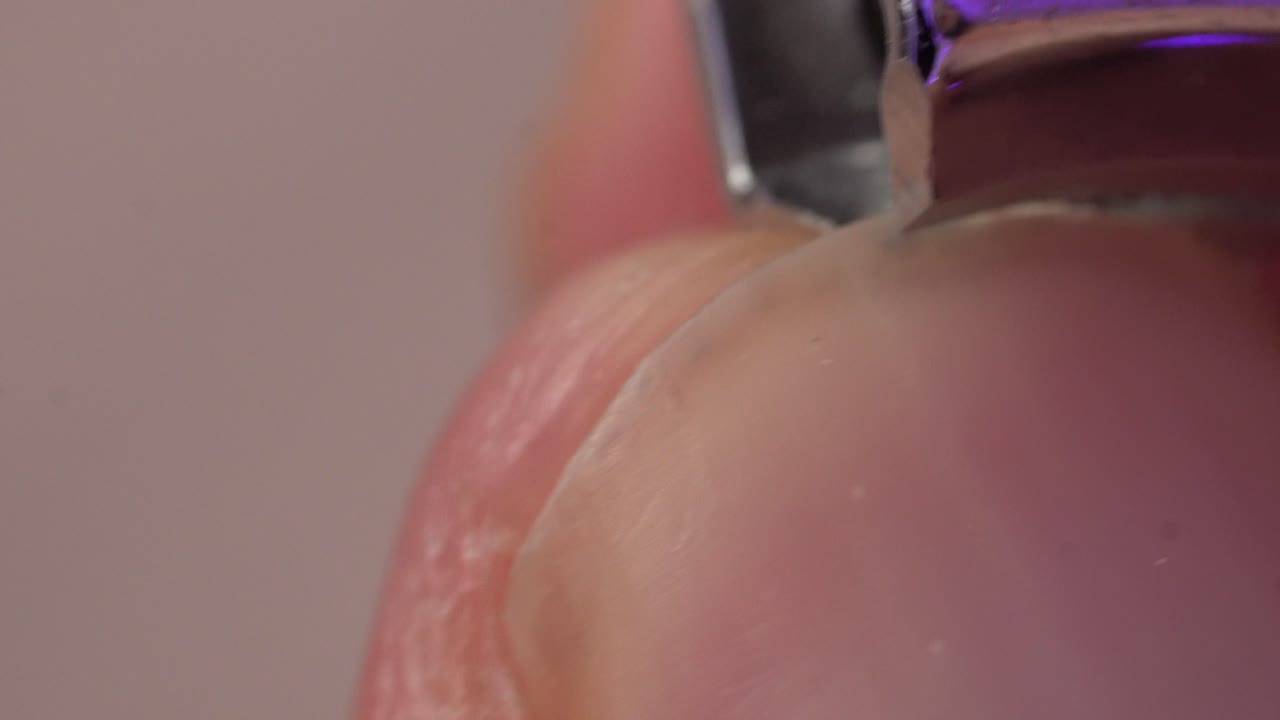 Extreme close up of a fingernail being trimmed with a metallic nail clipper, showing detail and precision