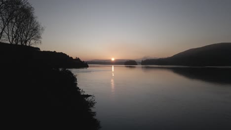 shot of beautiful sunrise on the edge of the lake with hills in the background