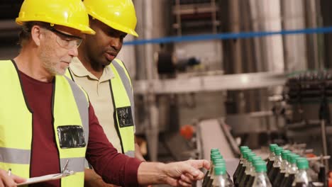 trabajadores chequeando botellas de jugo en la línea de producción