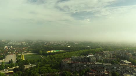 Morgennebel,-Der-Vom-Stadtpark-Aufsteigt,-Mit-Einem-Fußballstadion-In-Der-Ferne