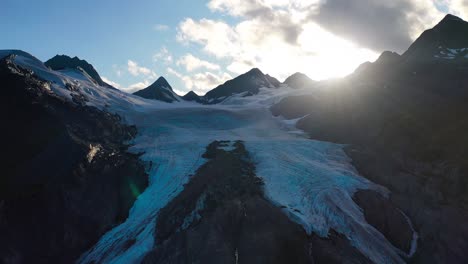 Luftnahaufnahme,-Die-Im-Sommer-In-Alaska-Am-Schneebedeckten-Berggipfel-Vor-Der-Strahlenden-Sonne-Entlanggleitet