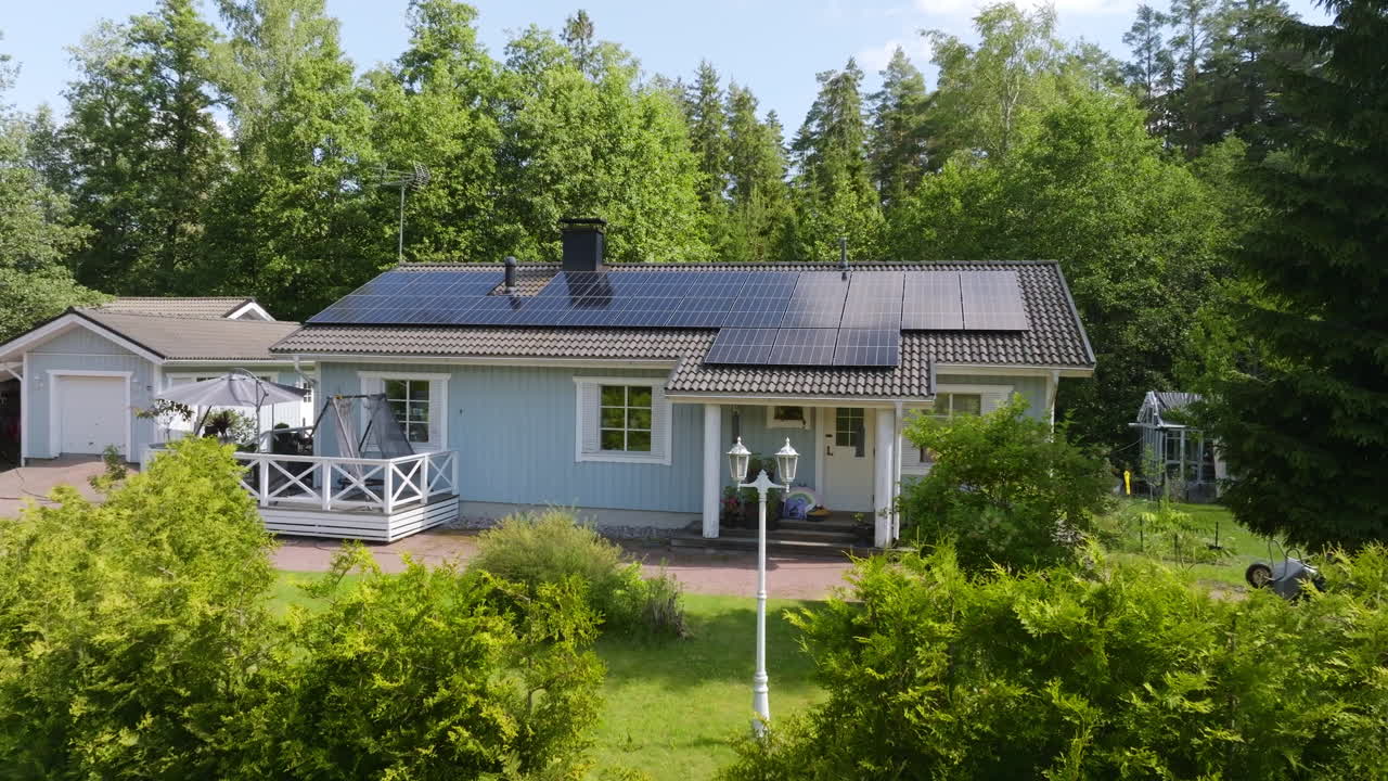 Drone flying low in front of a house with photovoltaic system and lush green yard
