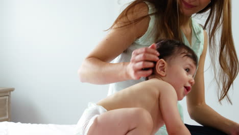 Cute-mother-keeping-a-close-watch-on-her-baby-playing-on-a-bed