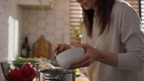 Caucasian-middle-age-woman-standing-in-kitchen-and-making-a-soup