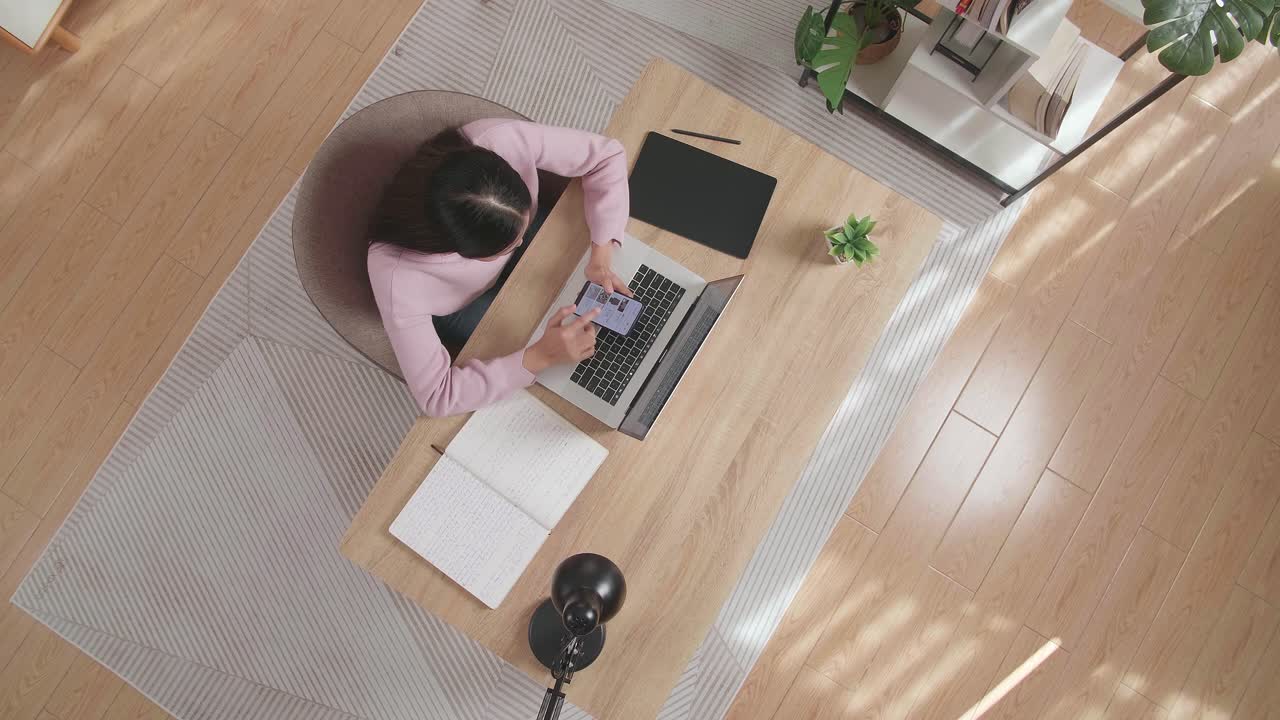 Top View Zoom Out Shot Of A Woman Using Smartphone While Sitting At The Wooden Desk At Home