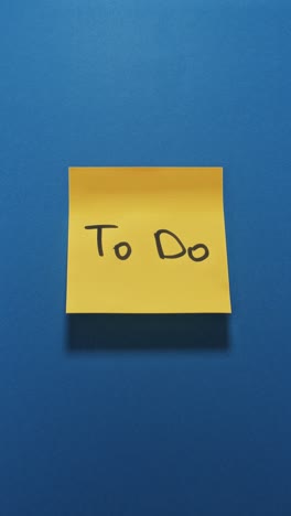 hands posting to do sticky note on blue wall, centering around organisation