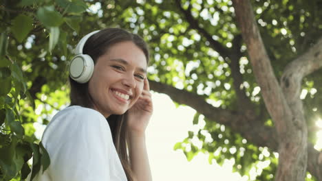 woman with earphones standing among trees
