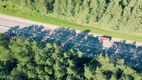 Aerial-Flying-over-the-highway-which-passes-cars-and-trucks-in-the-forest-Direction-to-the-auto-highway