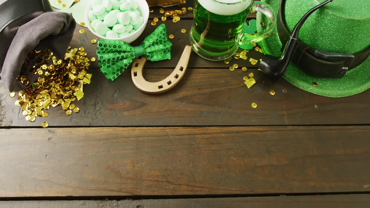 Video of st patrick's glass of beer, hat horse shoe with copy space on wooden background