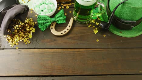 video of st patrick's glass of beer, hat horse shoe with copy space on wooden background