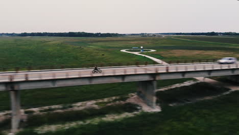 drone shot of motorcycle driving across bridge