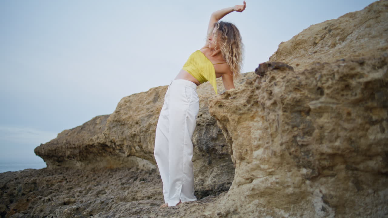 una coreógrafa bailando estilo moderno en rocas de piedra. una rubia rizada actuando