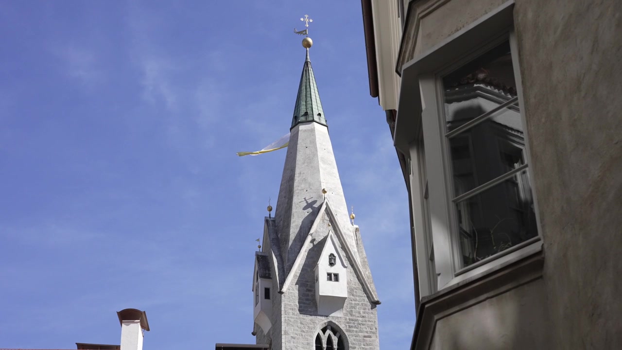 Den medeltida kyrkan i Brixen med en flagga i vinden