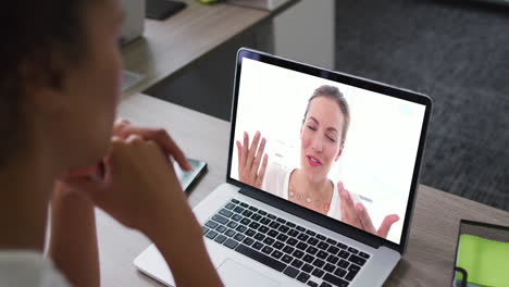 sección media de una mujer afroamericana haciendo una videollamada con una colega en una computadora portátil en la oficina