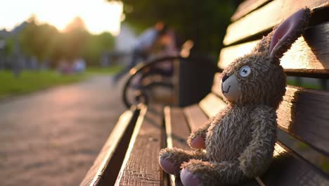 a soft, cuddly toy rabbit relaxing on a park bench as the sun sets, capturing a moment of nostalgia and peace in nature's embrace