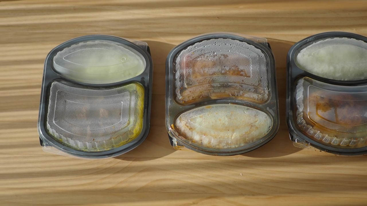 Drie plastic afhaalbakjes op een houten tafel