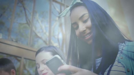 animation of bokeh over group of happy diverse teenager students using smartphones outdoors