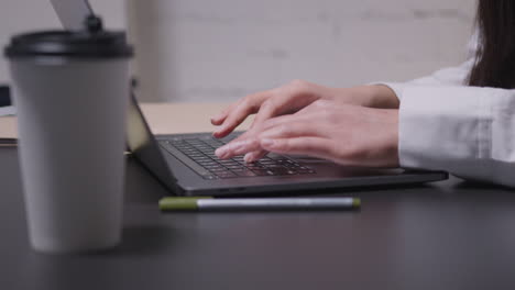 primer plano de una mujer irreconocible escribiendo en una computadora portátil durante una reunión de negocios