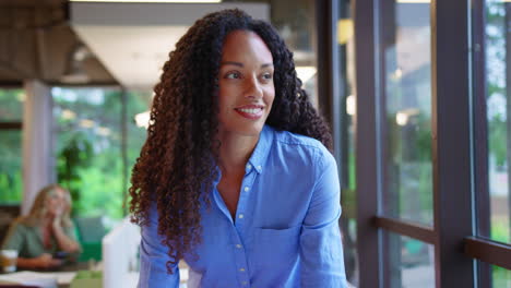 Businesswoman-Standing-At-Desk-In-Office-Looking-Out-Of-The-Window