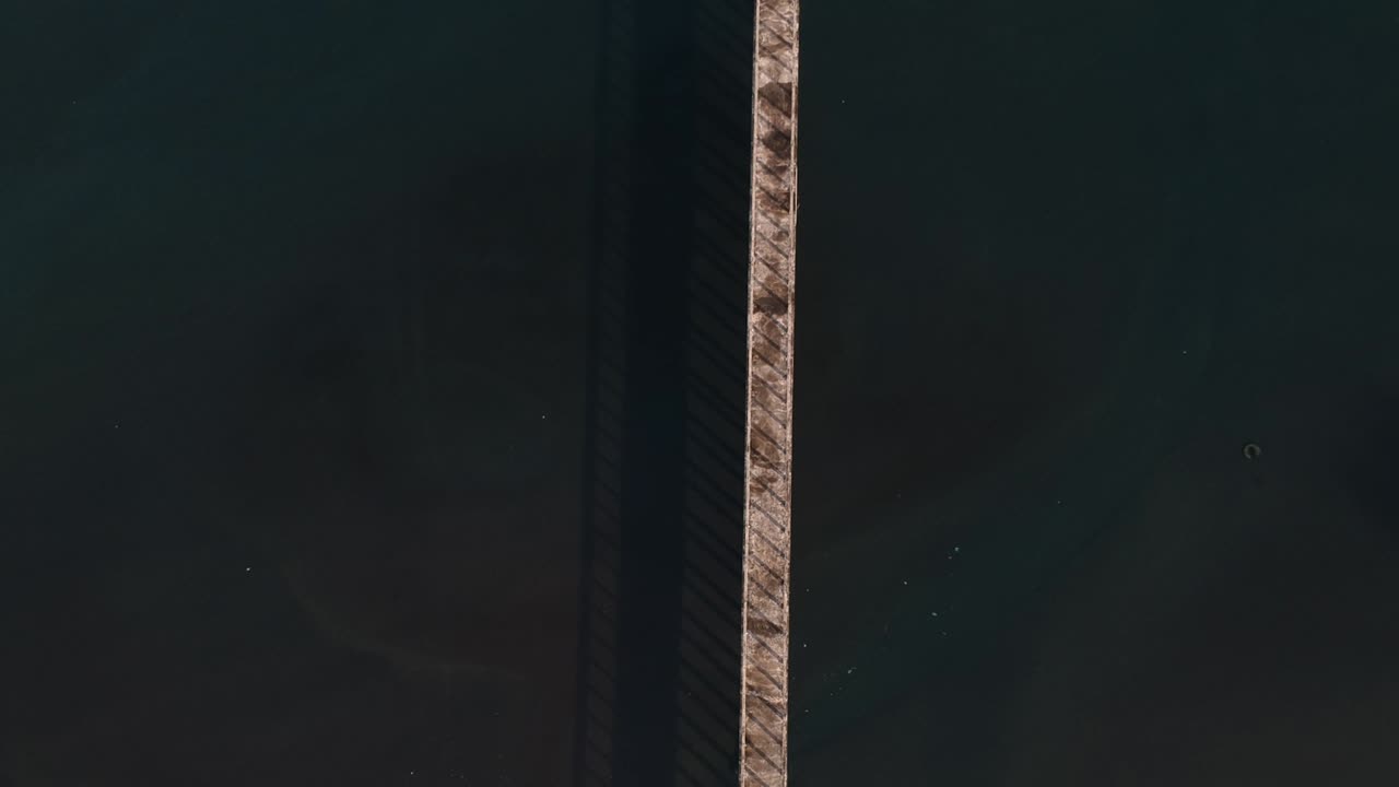 오염된 물이 주변을 둘러싸고 있는 바다로 향하는 긴 산책로 부두의 높은 드론 전망