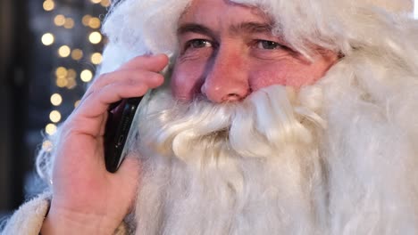 funny man in costume of santa claus talking on cellphone face close up portrait of santa claus talking on a smartphone funny man in costume of santa claus talking on cellphone face close up