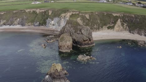 Aerial-orbits-headland-jutting-into-sea-on-south-coast-of-Ireland