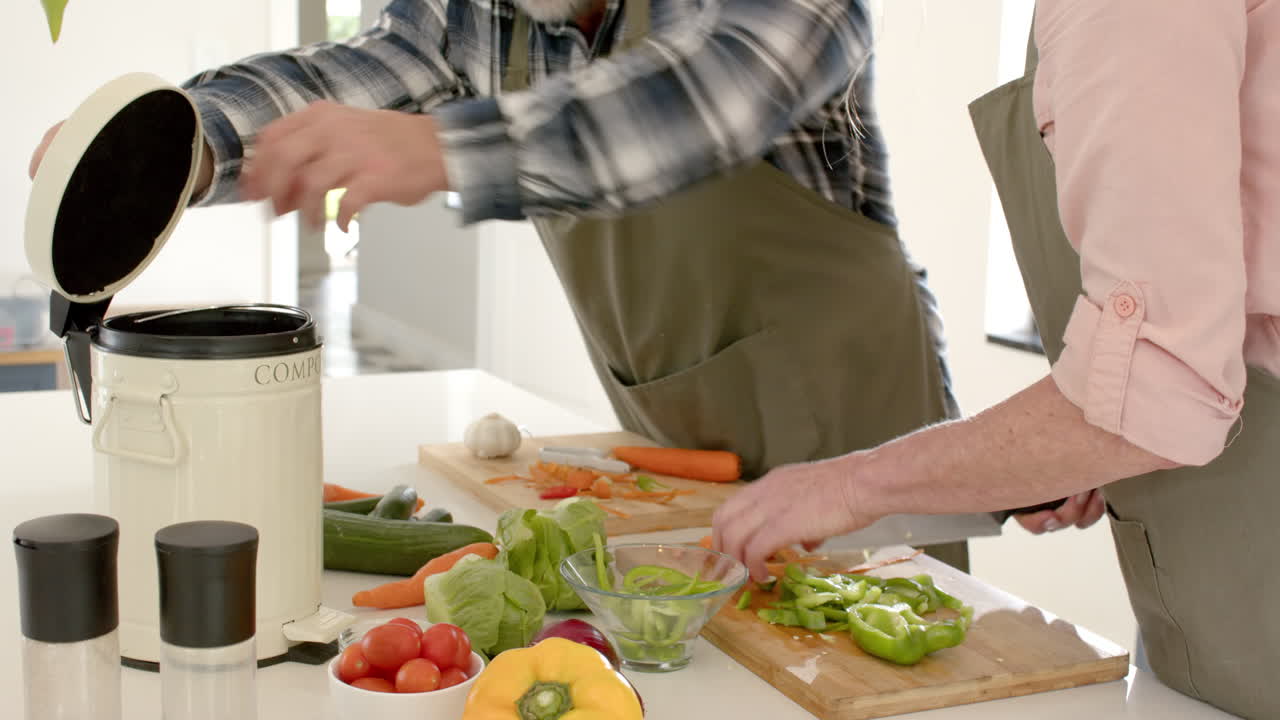 Preparing fresh vegetables, mature couple composting kitchen scraps at home