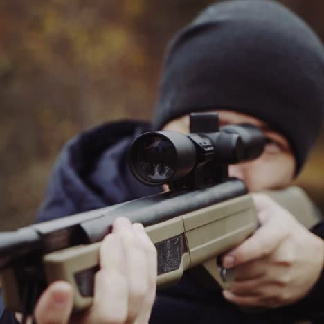 hombre disparando un arma en el bosque