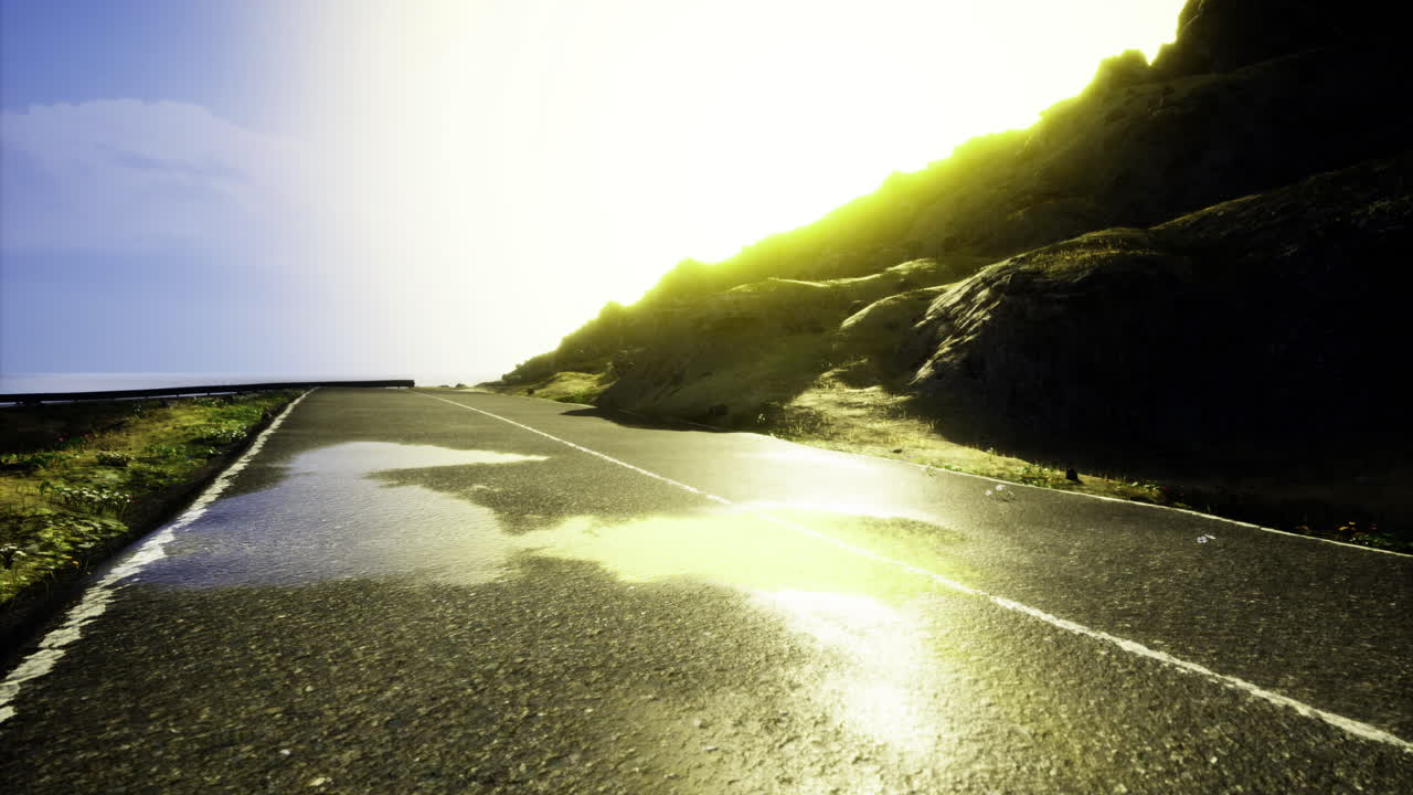 Sunset light reflecting on a wet road next to a grassy hill
