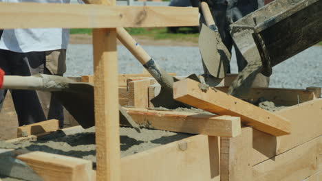 Arbeiten-Mit-Beton-Auf-Der-Baustelle-Arbeiter-Nehmen-Beton-In-Eine-Holzform-Schwere-Manuelle-La