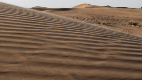 arena en cámara lenta soplando sobre las dunas de arena del desierto de oriente medio