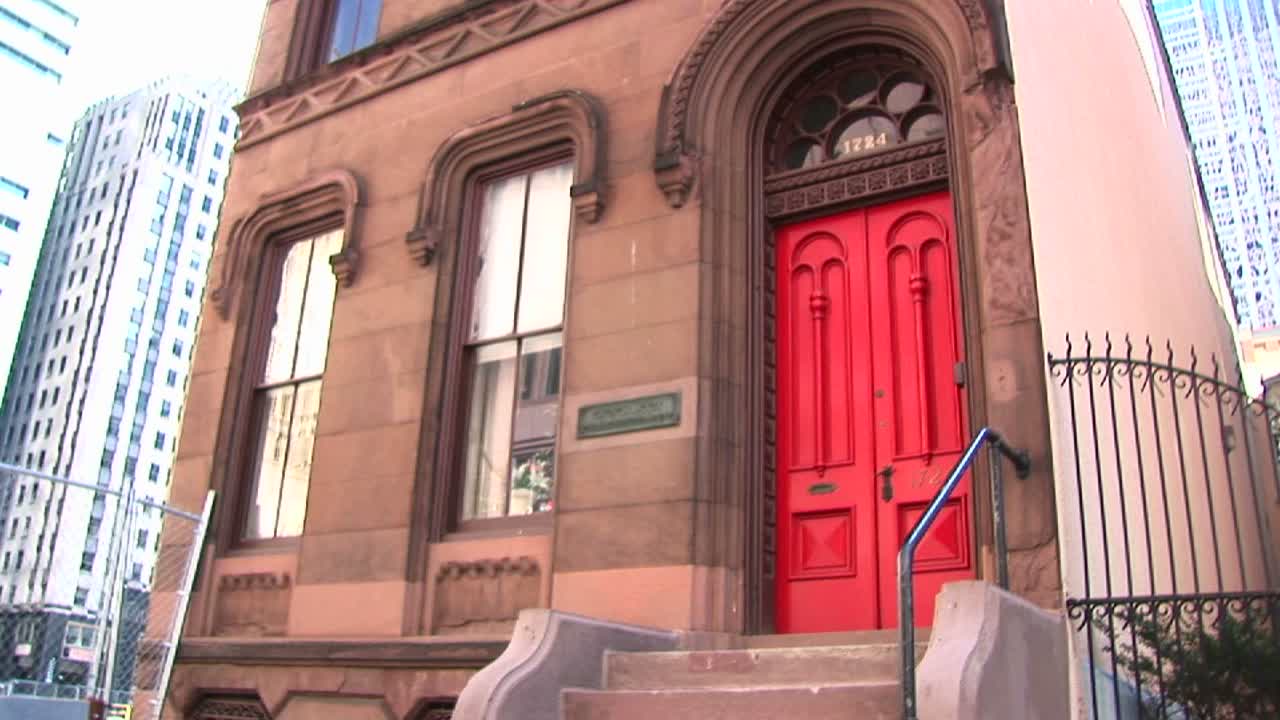 카메라는 한때 주거 지역이었던 고층 빌딩으로 둘러싸인 유서 깊은 오래된 브라운스톤 건물을 패닝합니다.