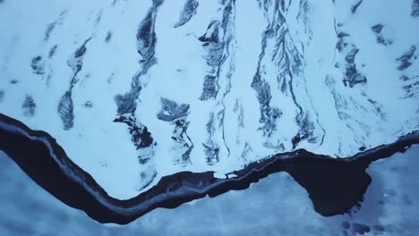 vista panorámica de drones montaña congelada y río que fluye junto a un lago helado en suiza
