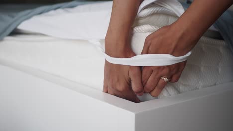 a woman makes a bed with white sheets