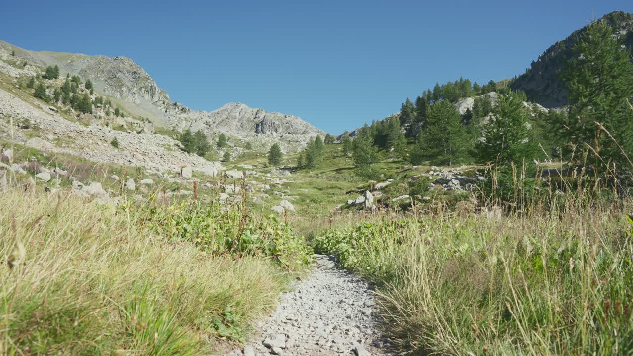 un hombre caminando solo en un sendero de montaña con bastones de senderismo, caminando hacia la cámara