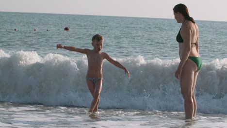 mother and son playing in the waves at the beach