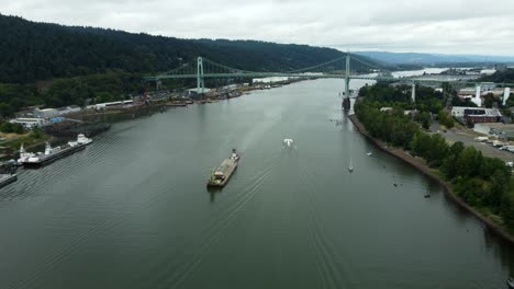 us, oregon, portland, st johns, 2025-07-26 - drone view of a barge being pushed by a tug on the willamette river under the bridge