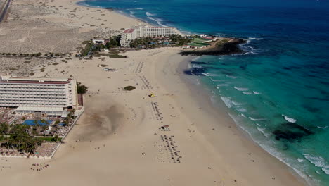 drone dolly in shot over the hotel complex overlooking the beach of corralejo, fuerteventura, canary islands