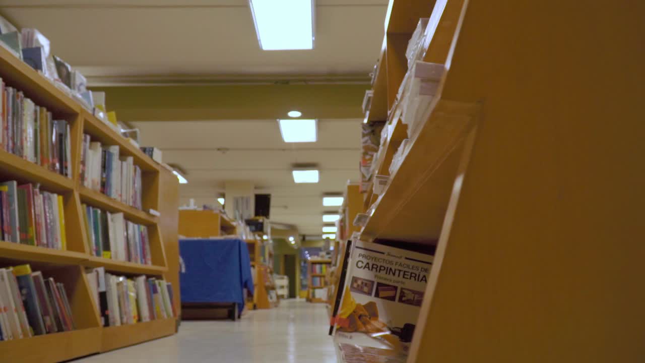 A slow slider shot revealing a hallway in a library filled with bookshelves and various titles