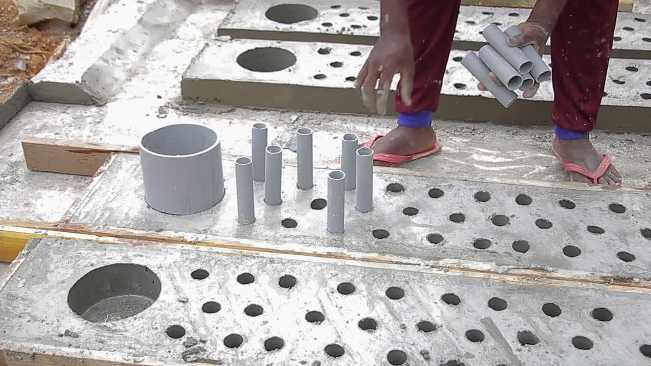 Indian mason worker removing PVC pipes from hardened concrete slab construction site
