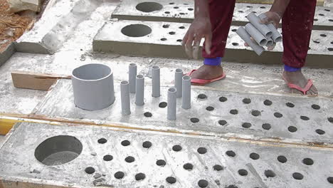 indian mason worker removing pvc pipes from hardened concrete slab construction site