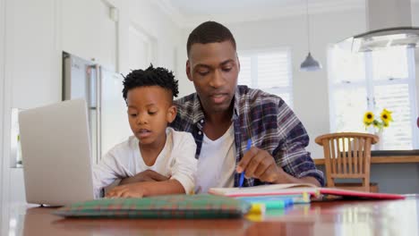 front view of black father helping his son with homework at comfortable home 4k