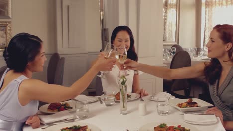 women toasting with white wine at dinner