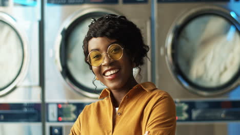 close up of beautiful young woman in yellow sunglasses smiling cheerfully to camera in laundry service room