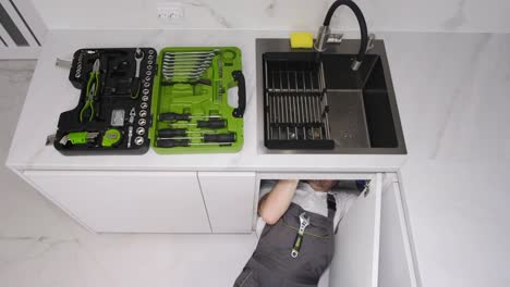 plumber repairing sink with tools