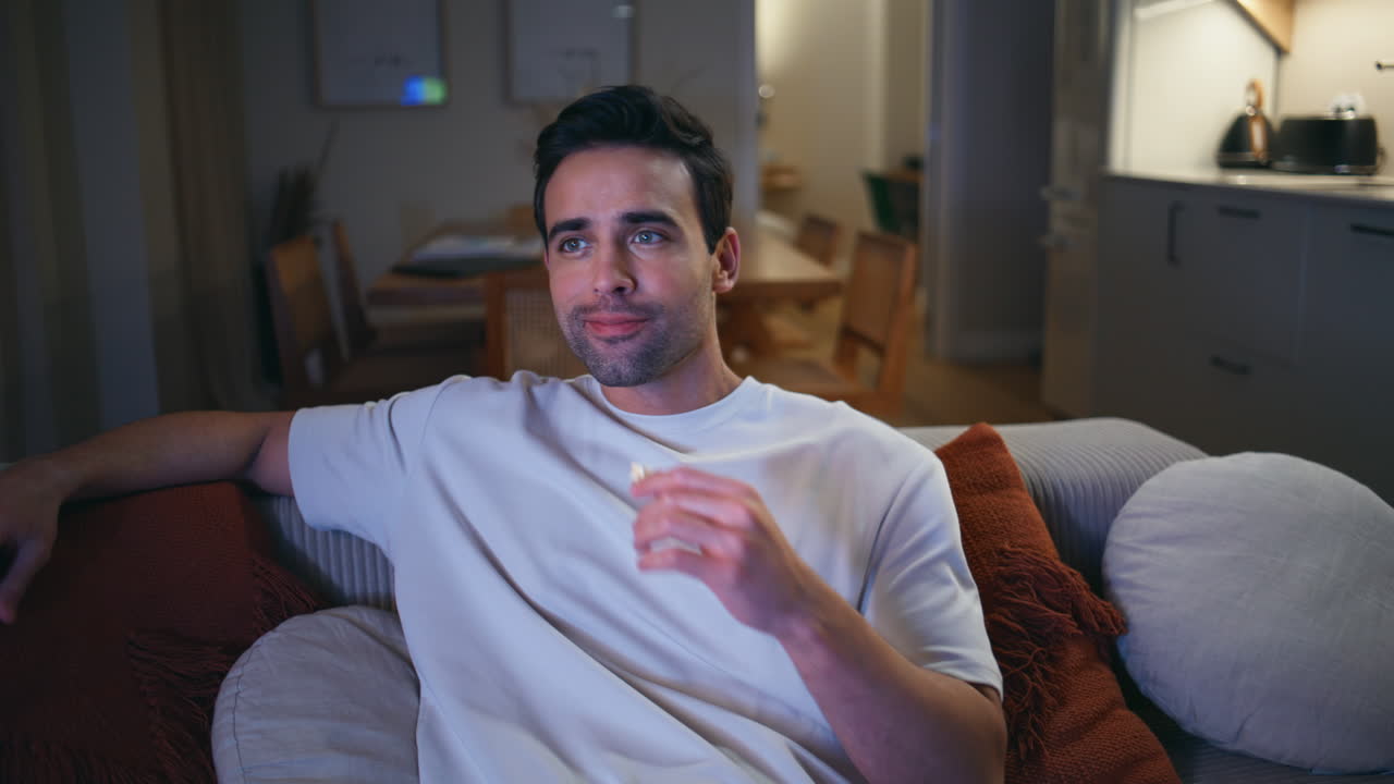 Uomo domestico che cambia canale con il telecomando sul comodo divano di casa